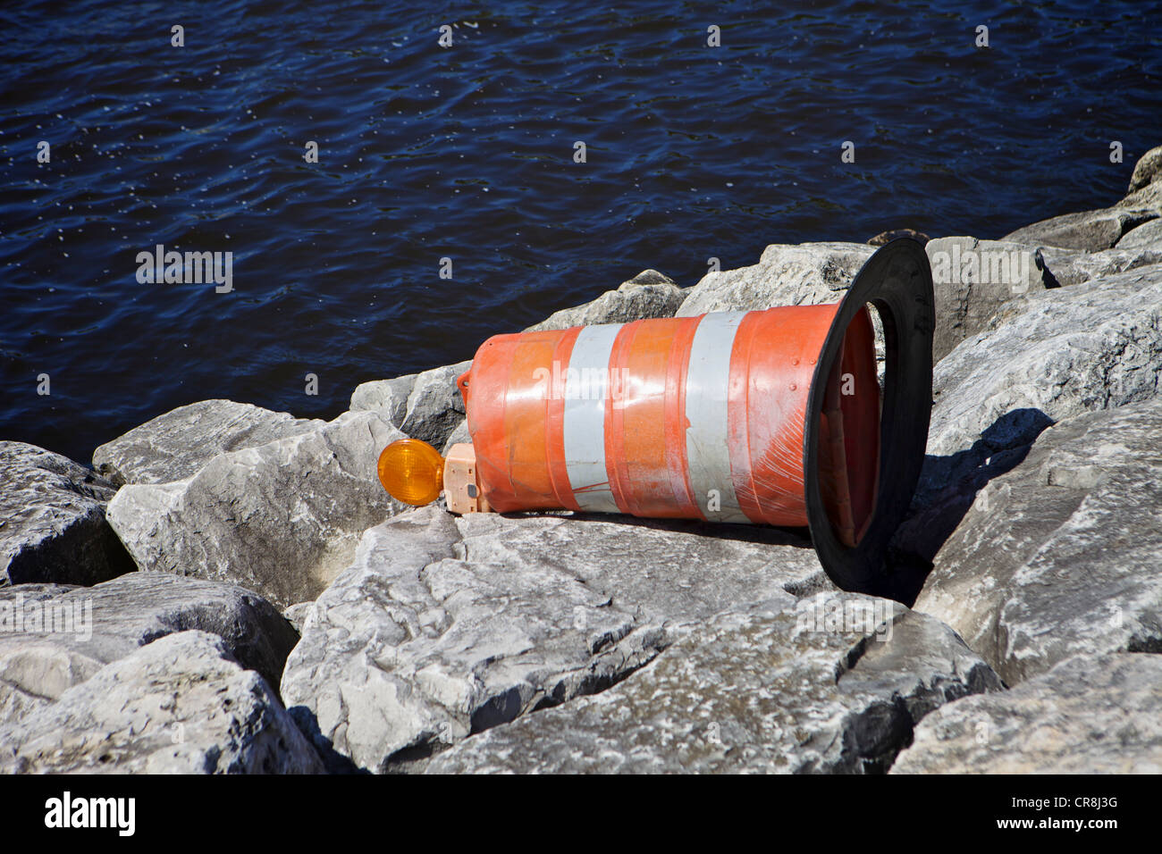road construction barrel laying on its side on a harbor breakwall Stock Photo