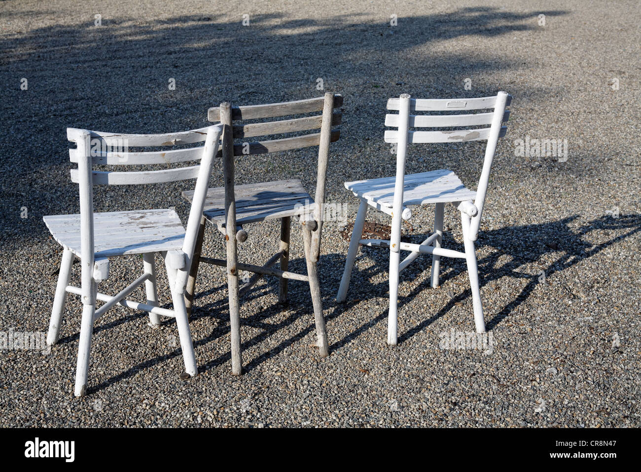 Three white wooden chairs standing side-by-side in a row Stock Photo