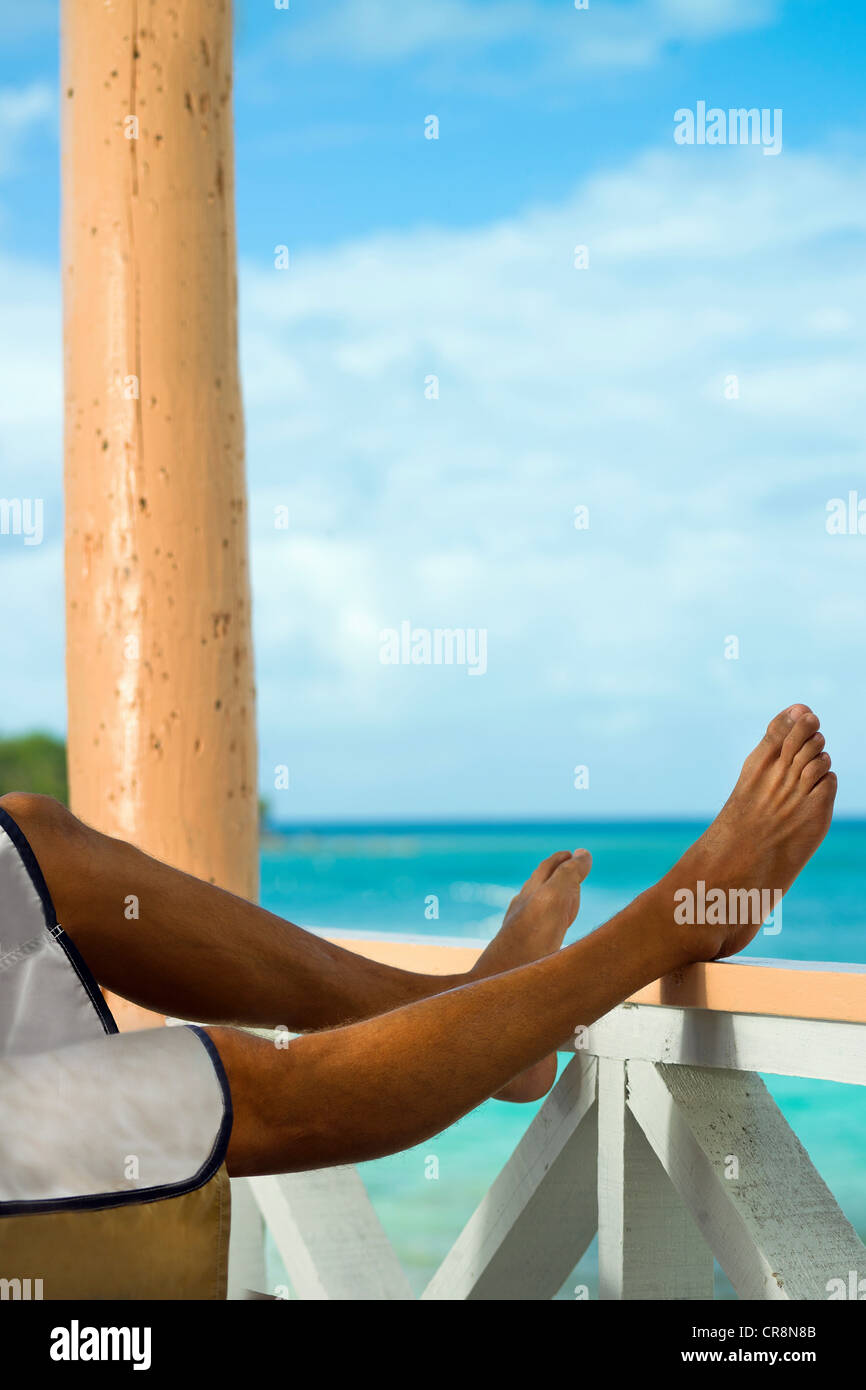 Man on vacation with legs resting on veranda rail Stock Photo