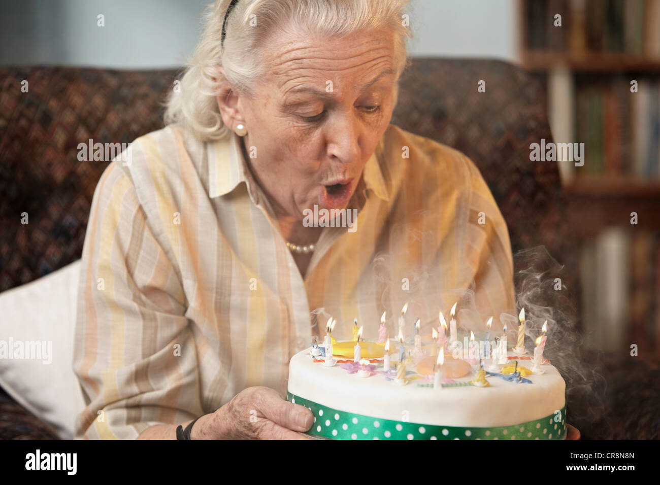 Old woman blowing out birthday candles hires stock photography and images Alamy
