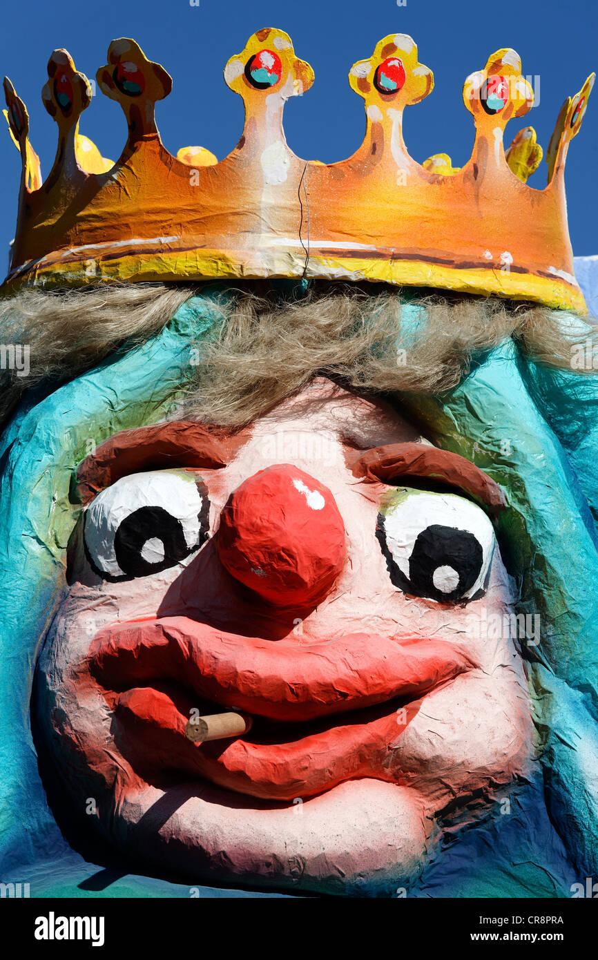 King wearing a crown with a comical facial expressions, smokes cigarillos, paper-mache figure, parade float at the Stock Photo