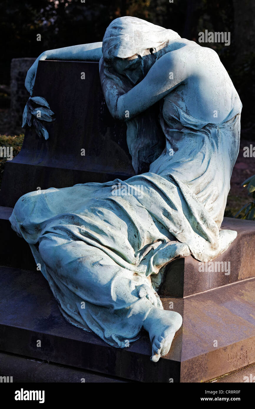 Sculpture of a grieving woman sitting on a grave stone, historic grave sculpture, Nordfriedhof Cemetery, Duesseldorf Stock Photo
