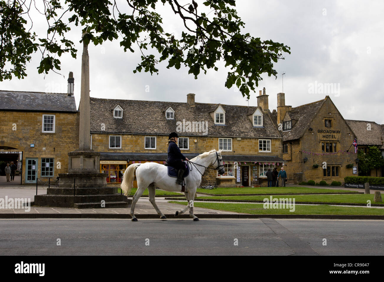 A horse and rider on their way down the High Street, Broadway , near the village centre, Cotswolds, UK. Stock Photo