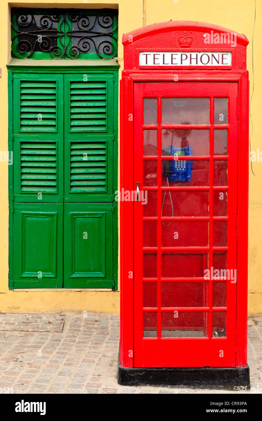 A Traditional Red English Phone Box In Front Of Yellow Wall And A