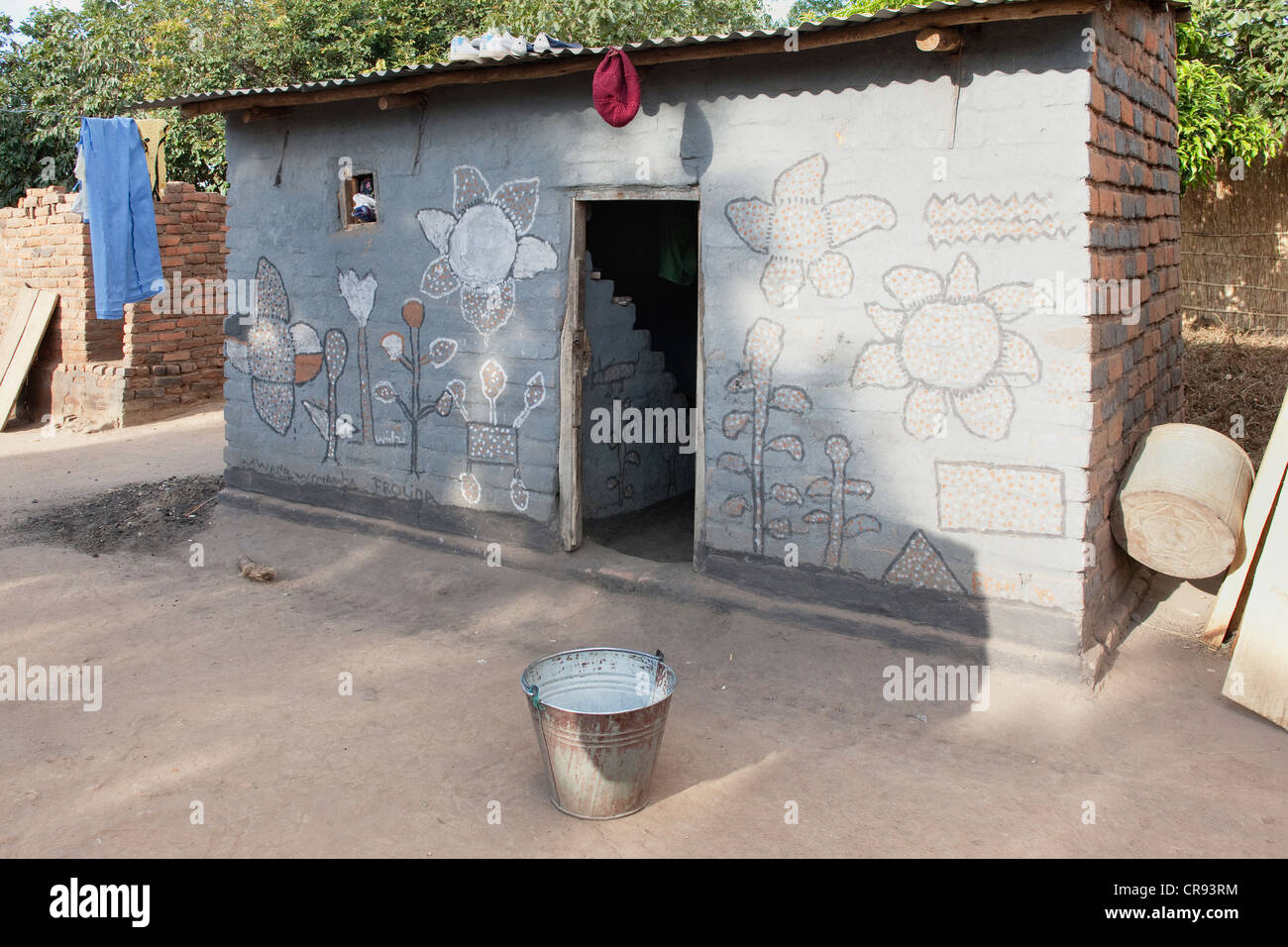 Mphunda Community. A rural village. A house with whitewashed walls and tin roof. Small bucket, and household objects. Stock Photo