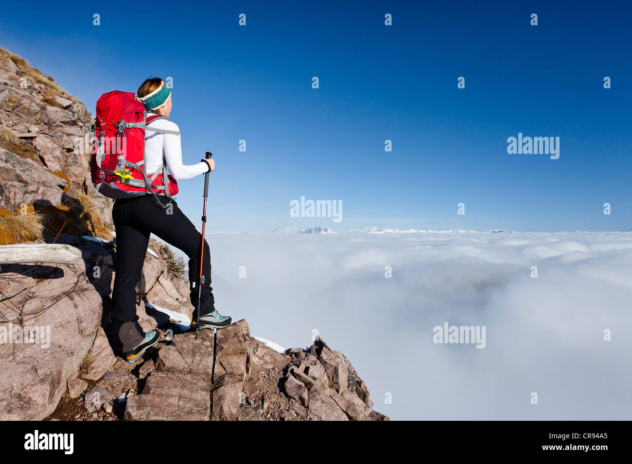 Hiker ascending Grossen Laugenspitze Mountain above Laugenalm alpine pastures, looking towards the Dolomites, Gampen Pass Stock Photo