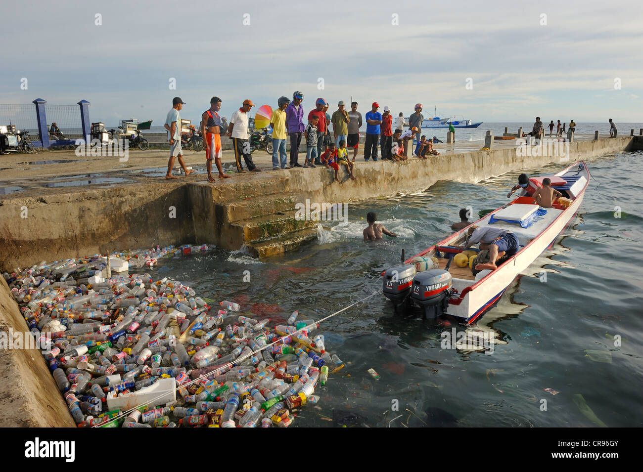 Fishermen landing their catch, taking it to the quay walls, floating plastic debris at front, Kota Biak, Biak Island, Irian Jaya Stock Photo