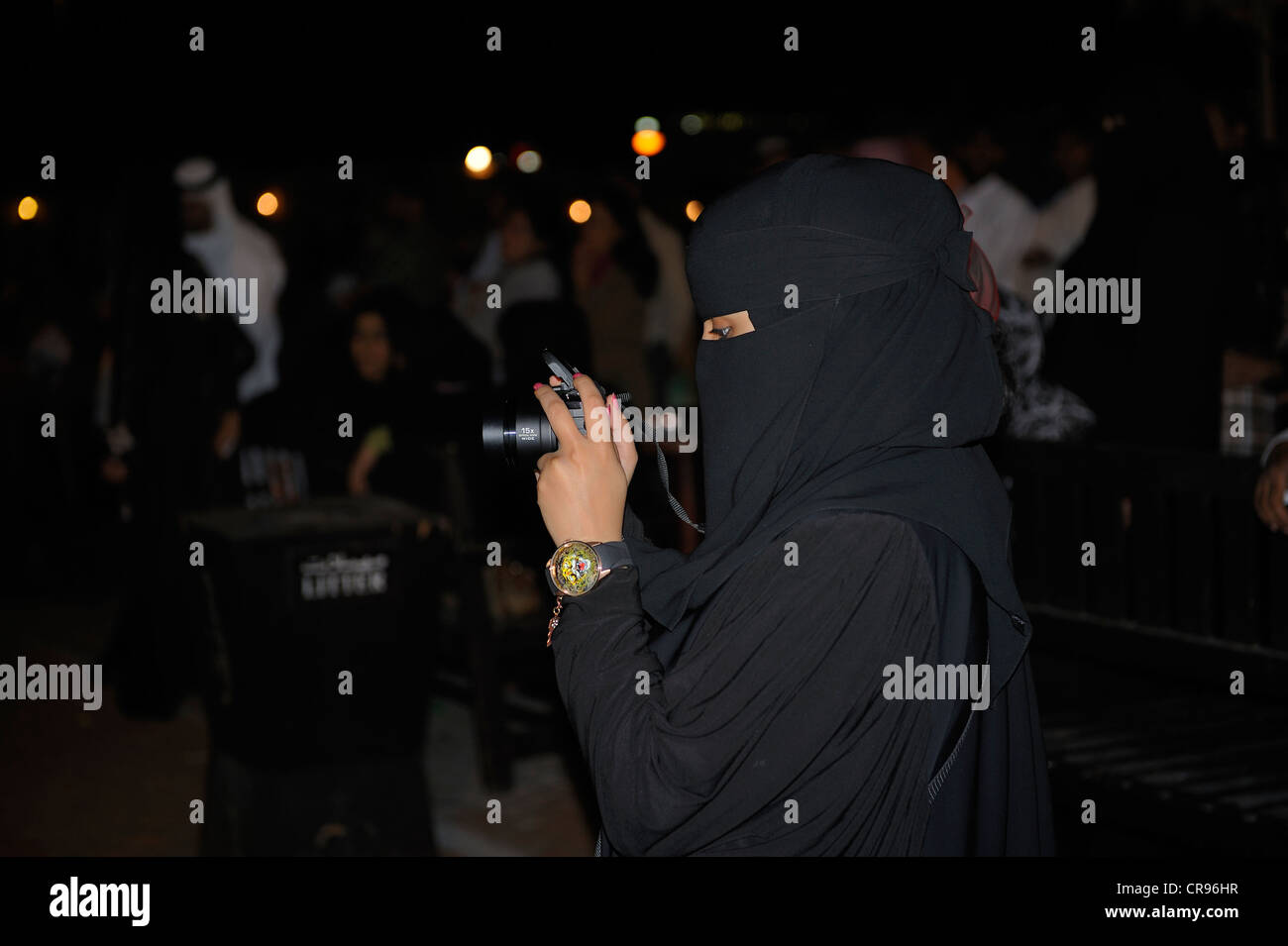 Woman wearing a hijab, head and body covering, taking photographs