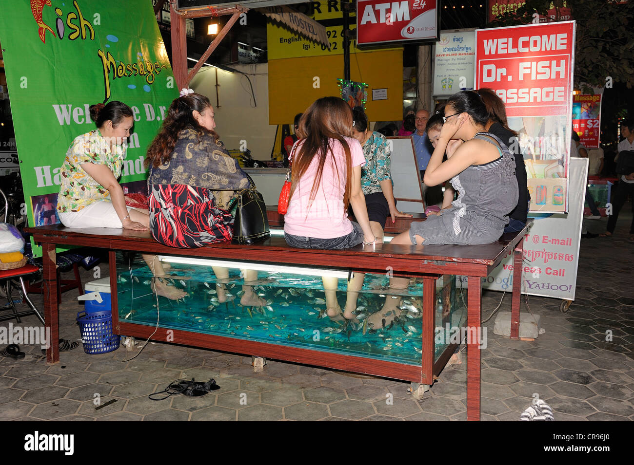 Khmer women getting a foot massage from doctor fish at the roadside, Siem Reap, Cambodia, Southeast Asia, Asia Stock Photo