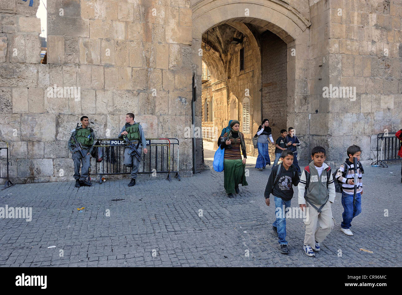 Israeli guards and Palestinian children with toy guns coming out from the Arab Quarter through the Lion Gate into the Old City Stock Photo