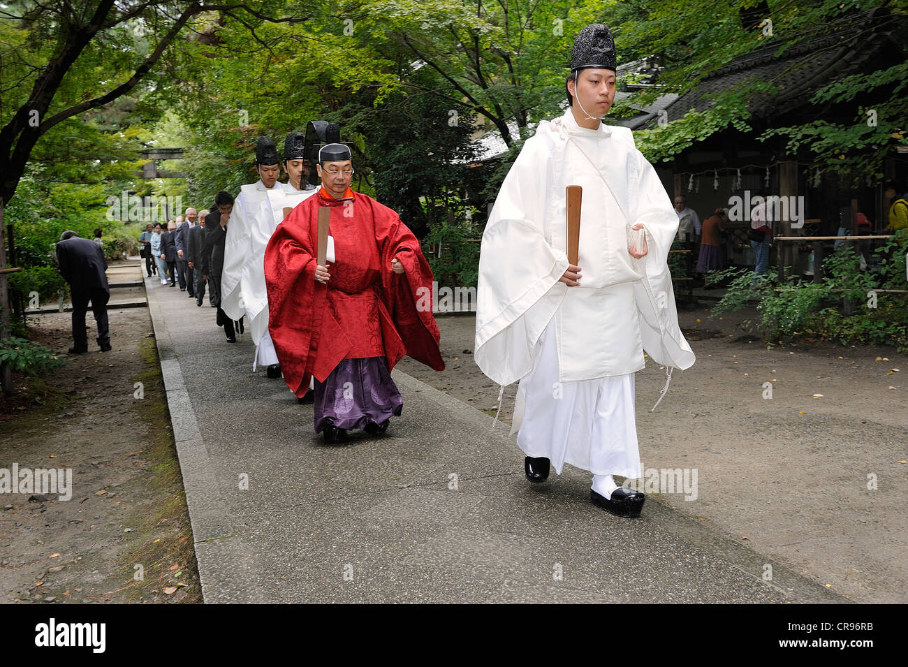 Shinto priests carrying scepters and wearing hats with community