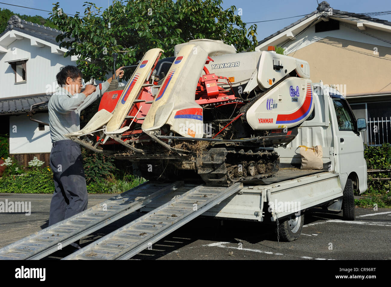Rice farmer loading his combine harvester on a small truck, Iwakura ...