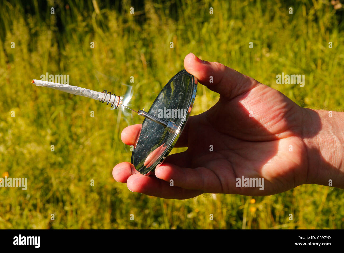 Hand holding a solar cigarette lighter, concave mirror Stock Photo