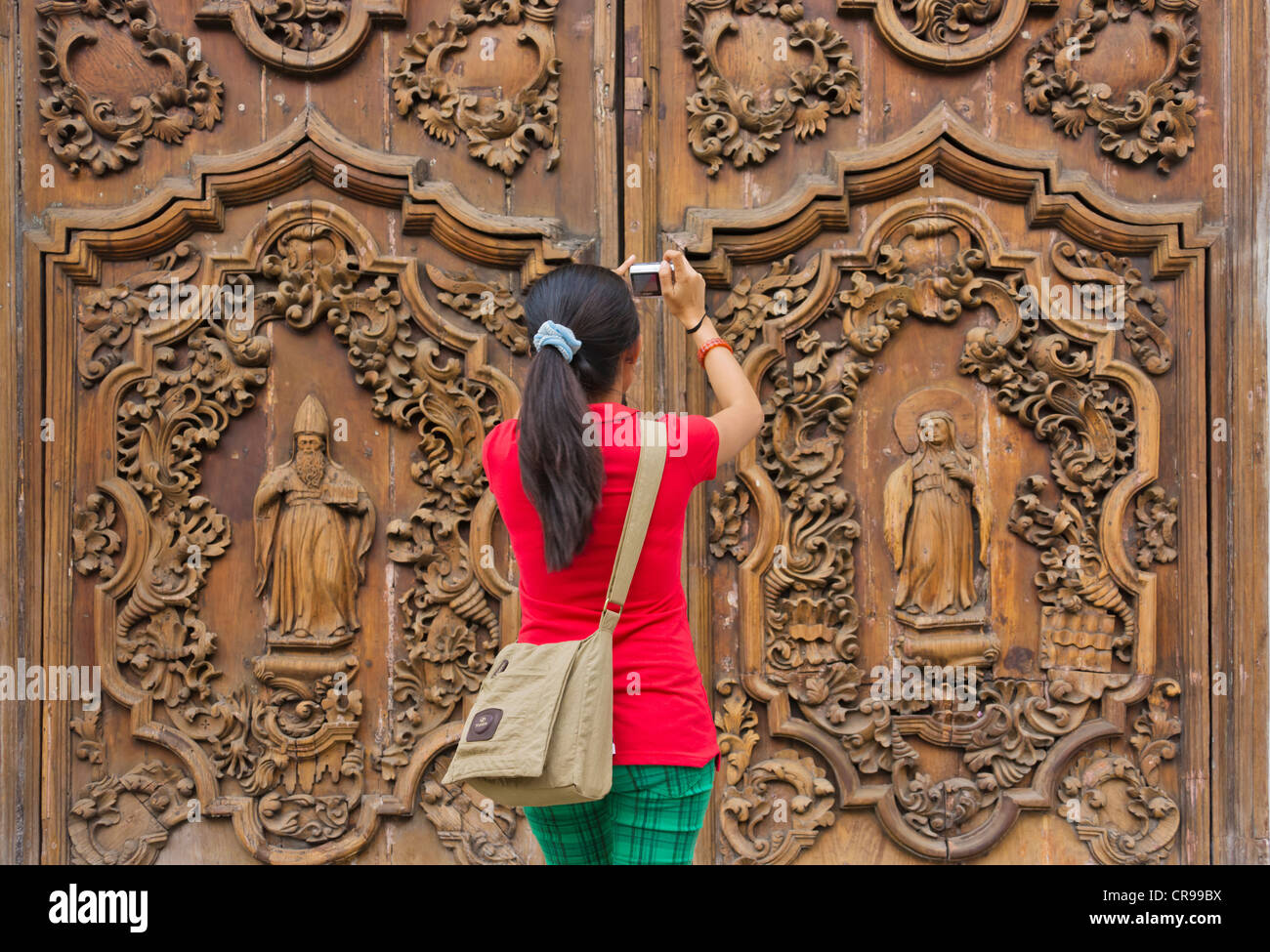 Tourist photographing the intricately carved wooden door at the entrance to Manila Metropolitan Cathedral, Manila, Philippines Stock Photo