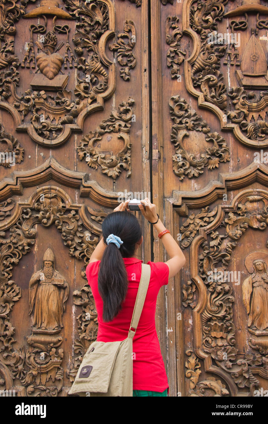 Tourist photographing the intricately carved wooden door at the