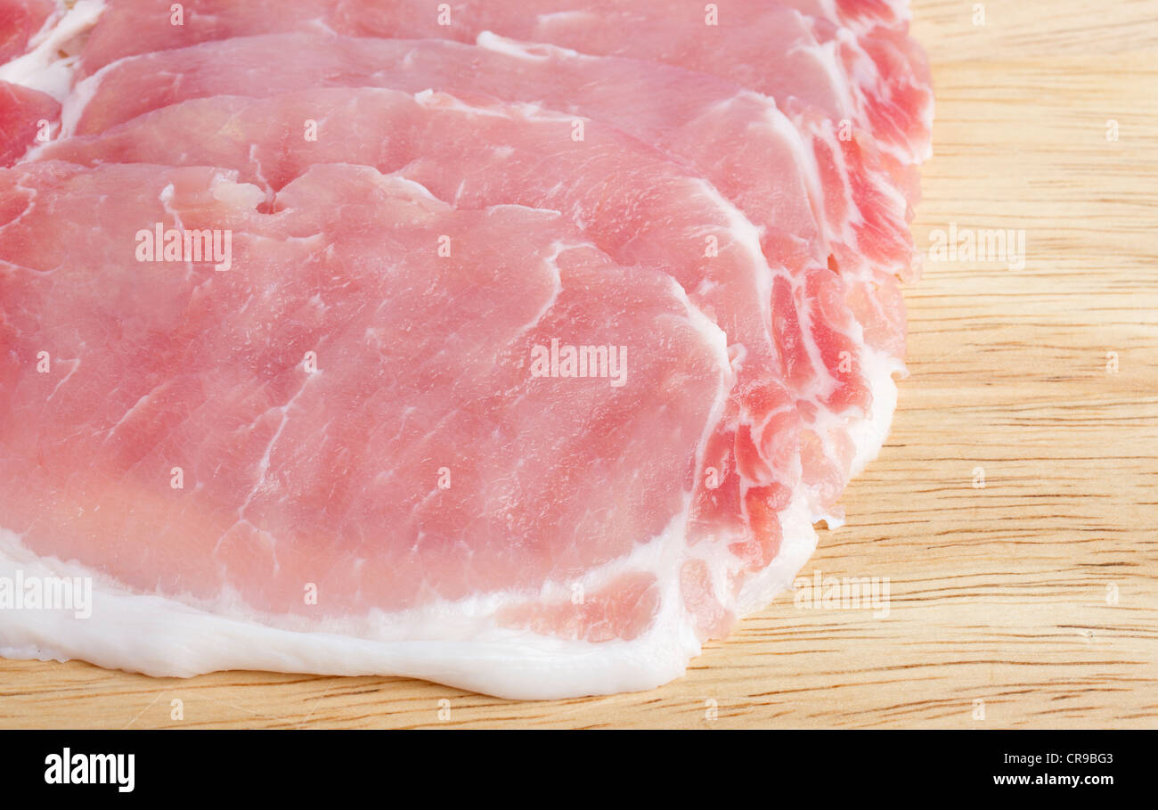Several rashers of bacon on wooden chopping block Stock Photo
