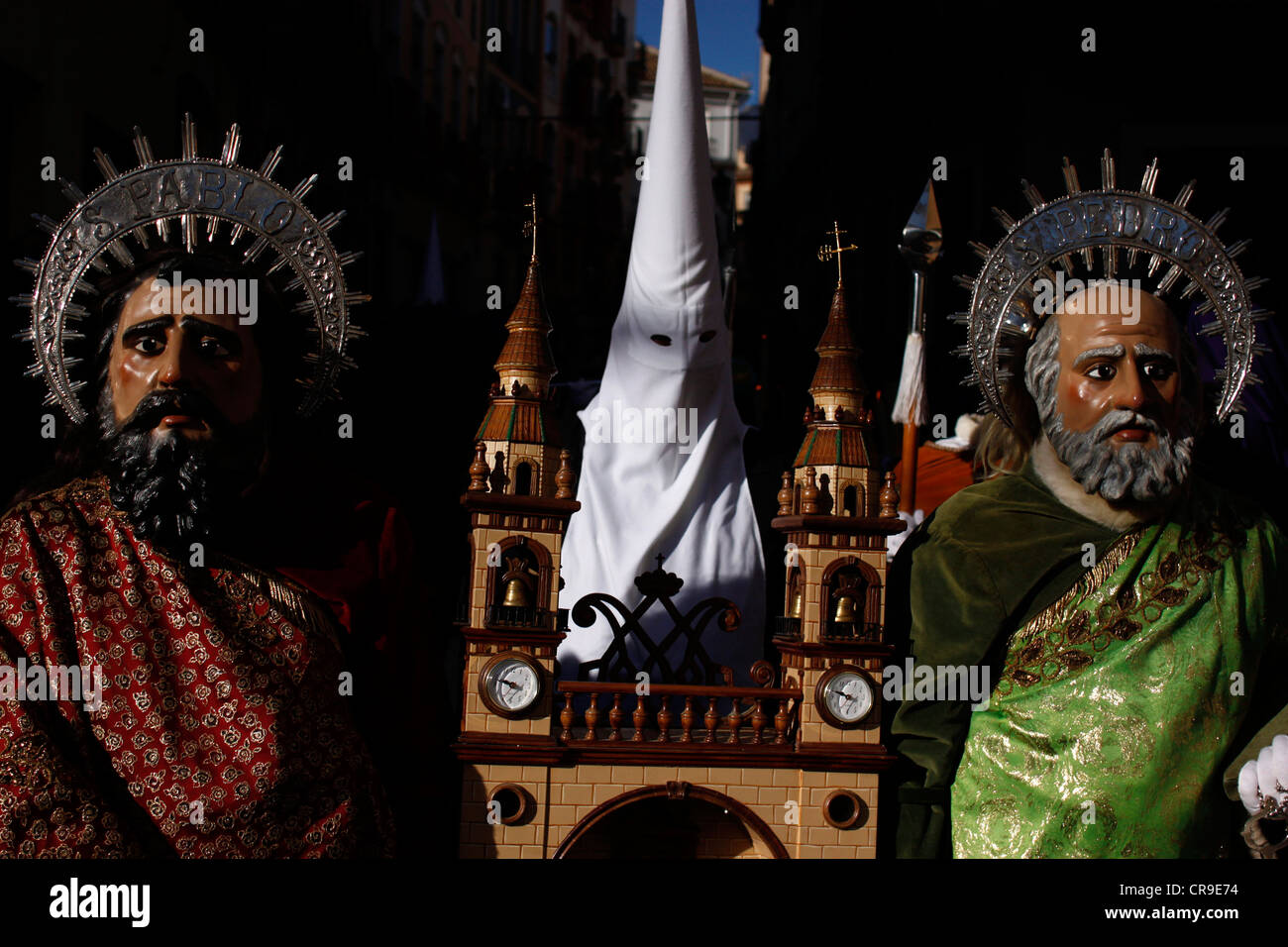 Masked men dressed as Saint Peter and Saint Paul hold a small scale church during an Easter Holy Week in Puente Genil, Spain Stock Photo