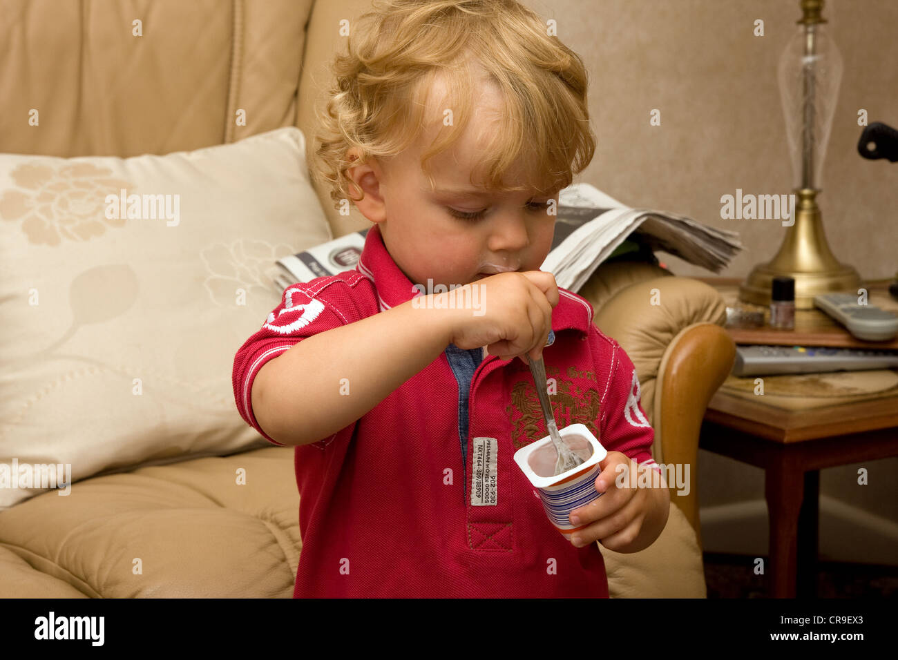 toddler eating spoon mouth looking down yoghurt Stock Photo Alamy
