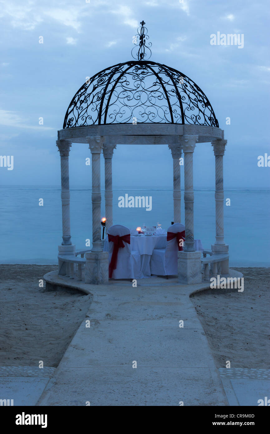 This is a wedding gazebo candlelight dinner setup on the beach for a