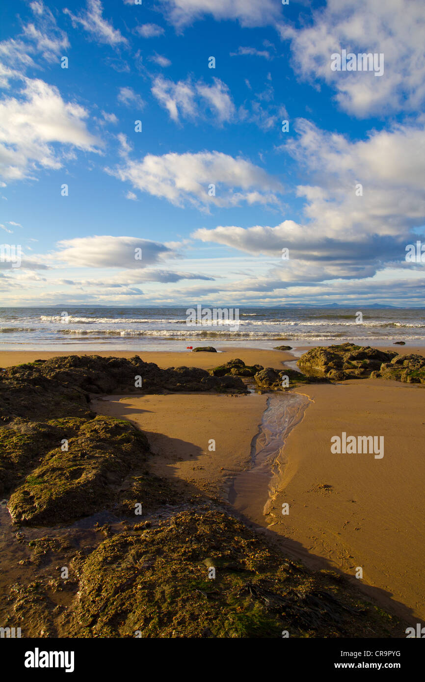 Scottish beach with algae covered rocks, yellow sand and blue skies. Stock Photo