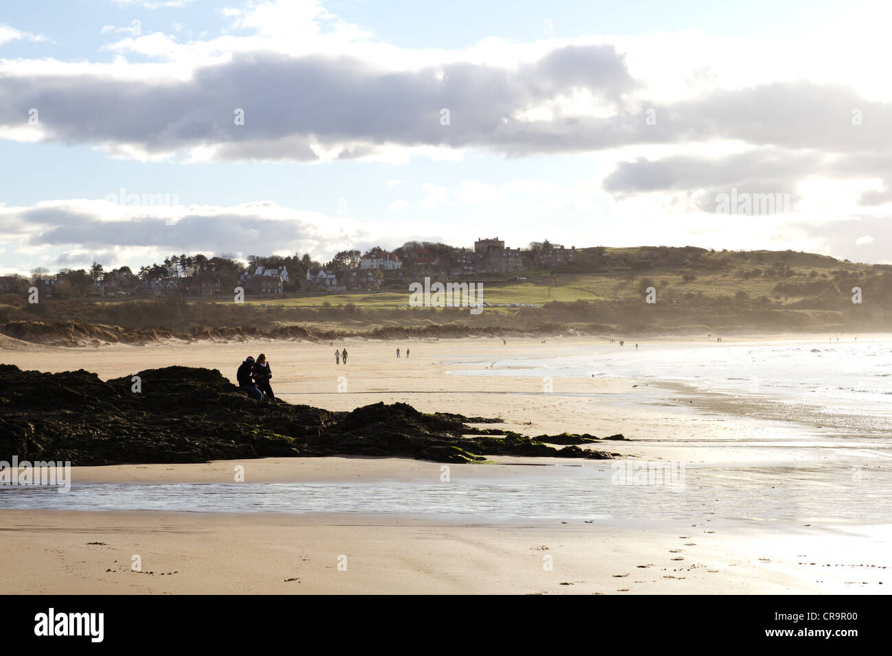 Silhouetted people sitting on the rocks of a warm Scottish beach in early summer. Stock Photo