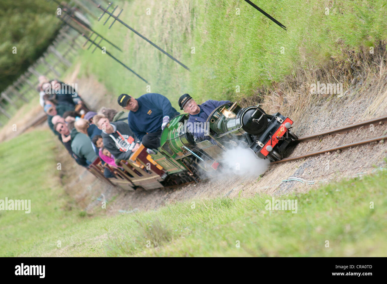 A miniature steam train putting a train of tourists at a country park ...