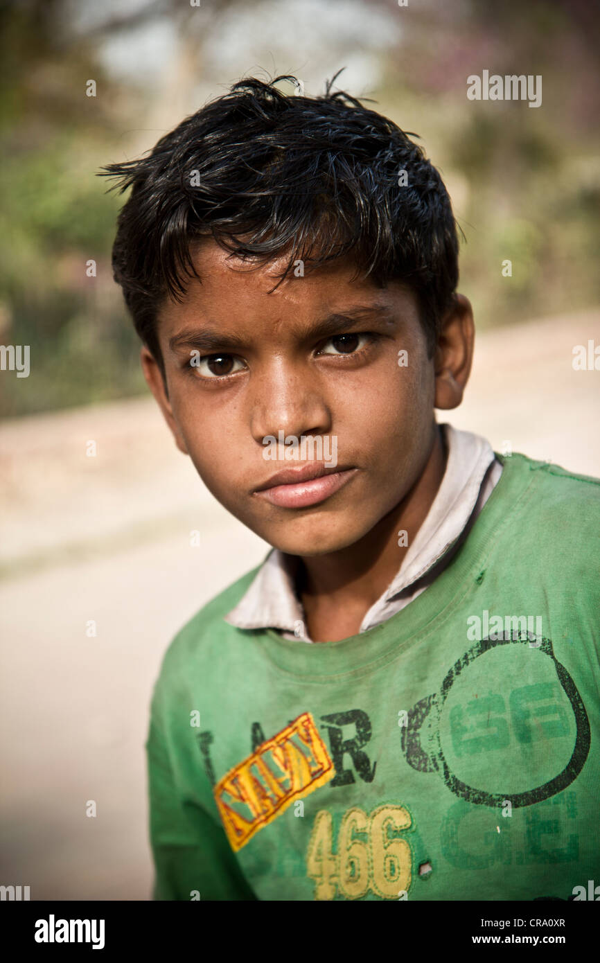 4 year old boy, wearing a denim shirt, jeans, looks at the camera, poses  for a photo. walkway Behind is a line of trees. Stock Photo | Adobe Stock