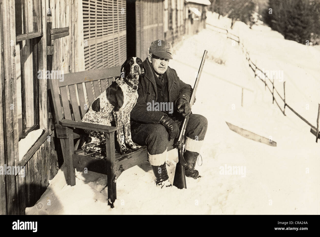 Older Hunter with Shotgun Sitting on Bench with his Hunting Dog Stock Photo