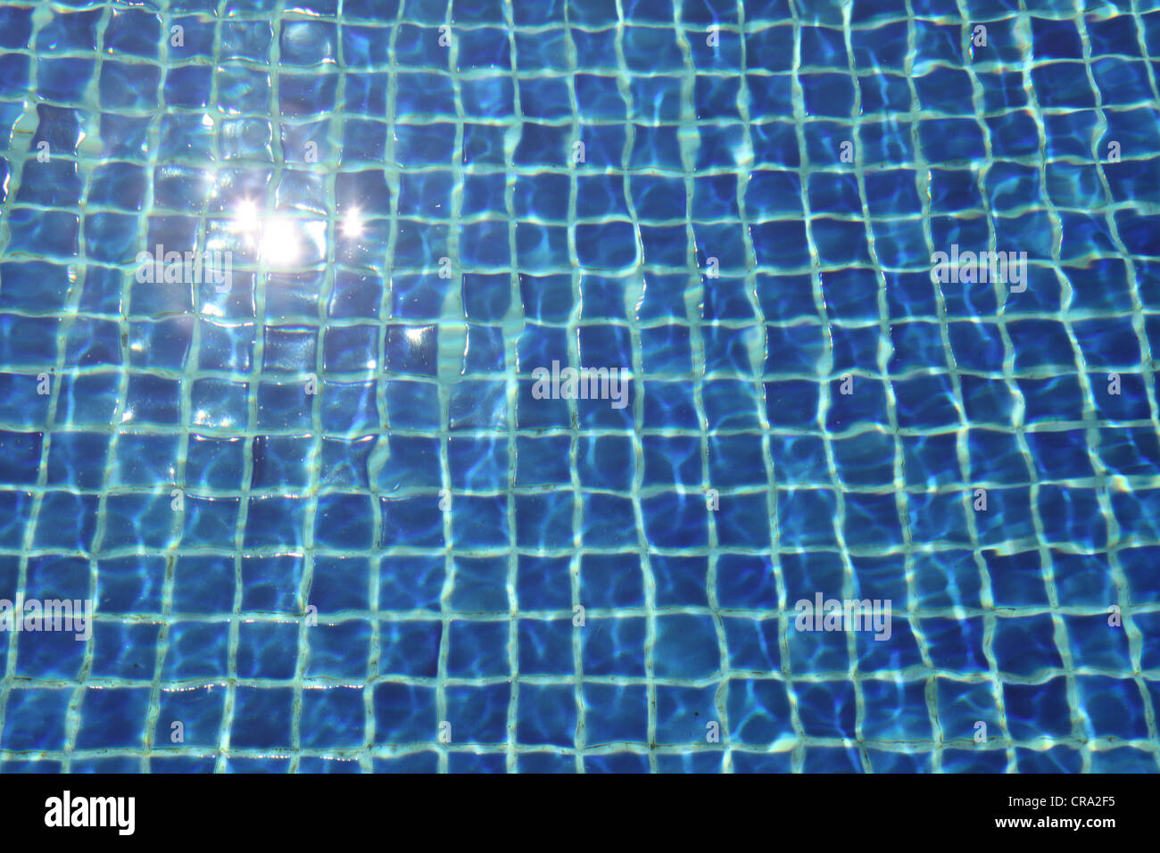 It's a photo of the water of a swimming pool with the blue tiles at the bottom of the pool. It's sunny and fresh visuals. day Stock Photo