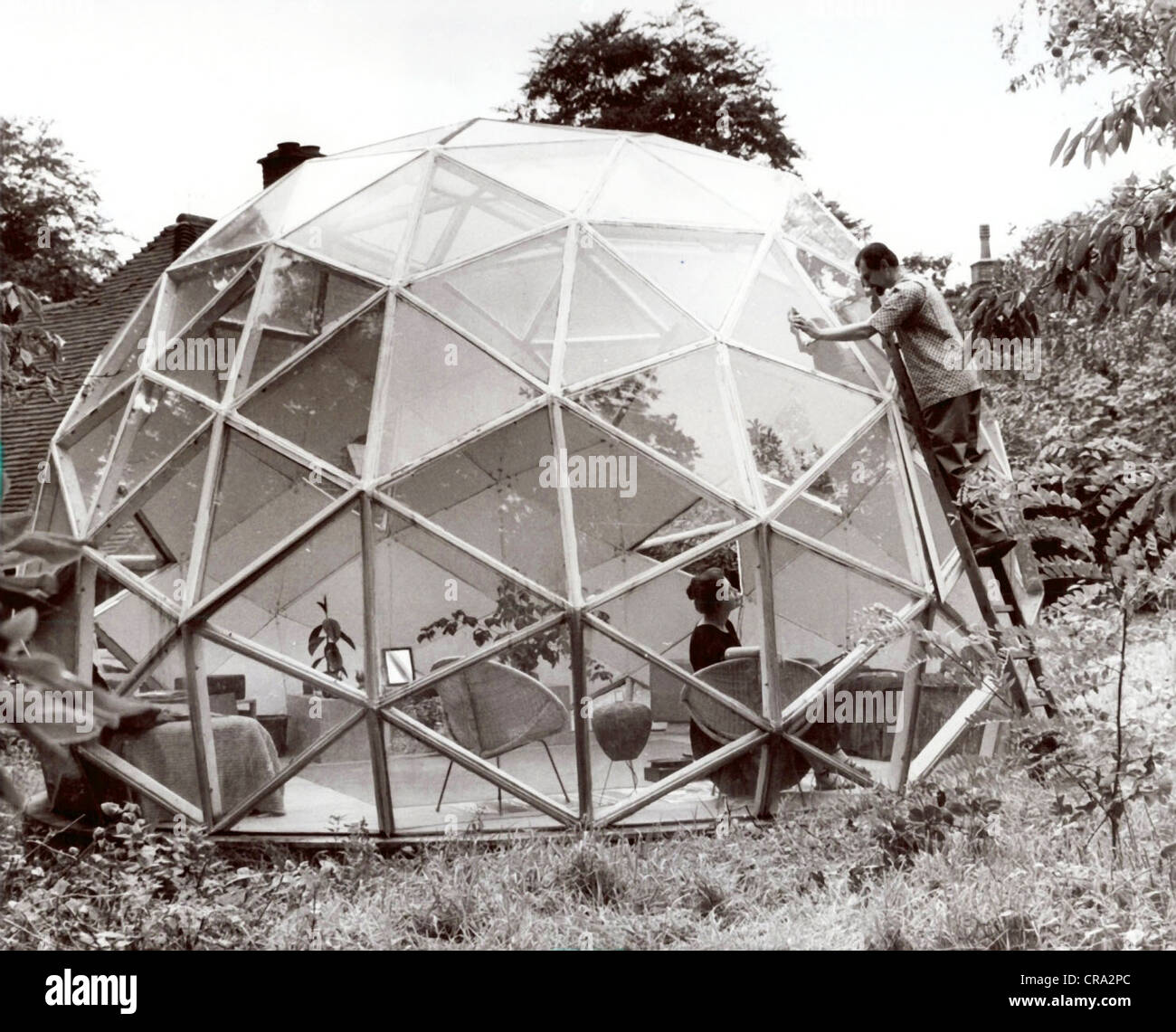 Husband Cleaning Windows on Geodesic Dome House Stock Photo