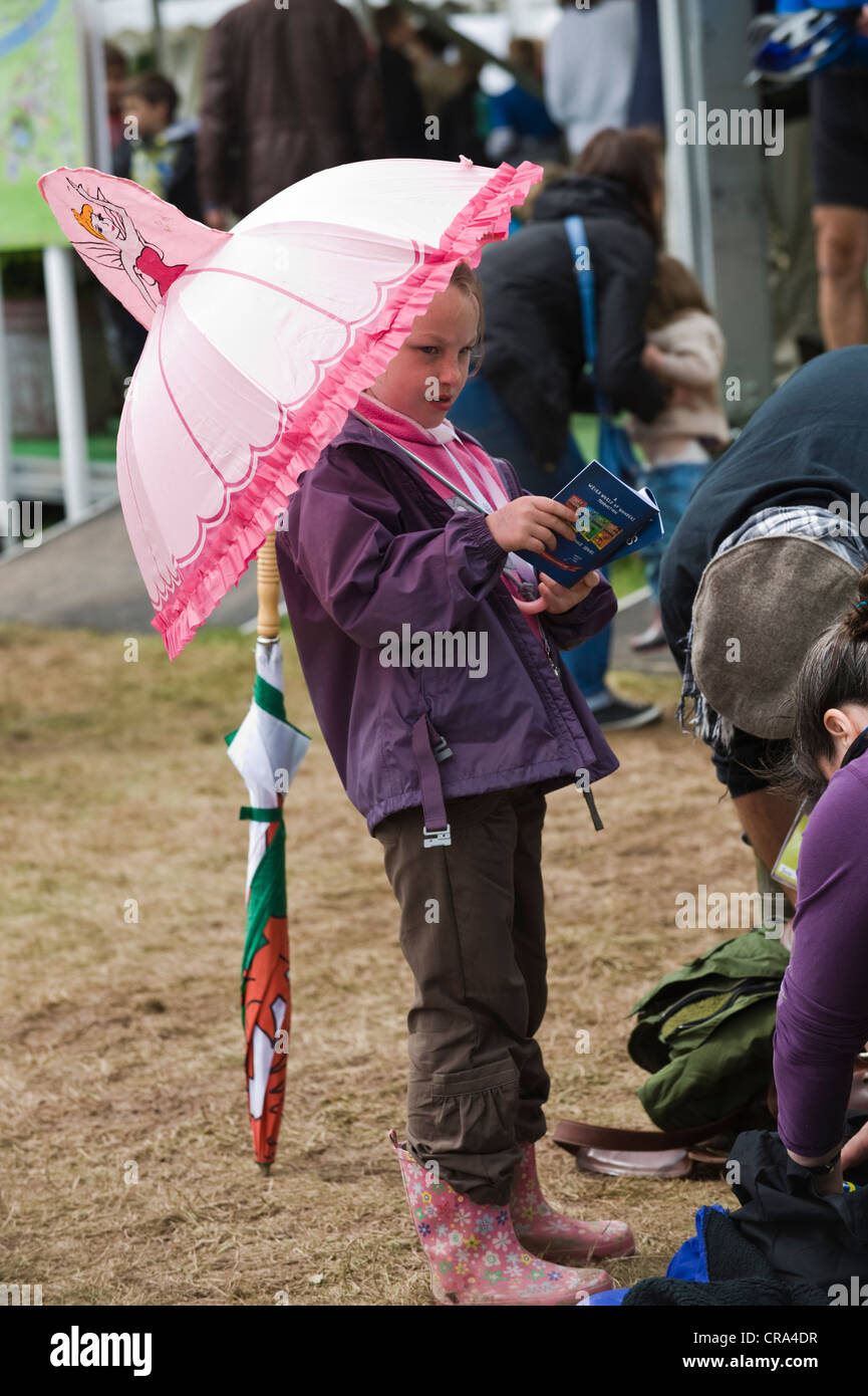 Young girl with novelty pink umbrella at The Telegraph Hay Festival 2012, Hay-on-Wye, Powys, Wales, UK Stock Photo
