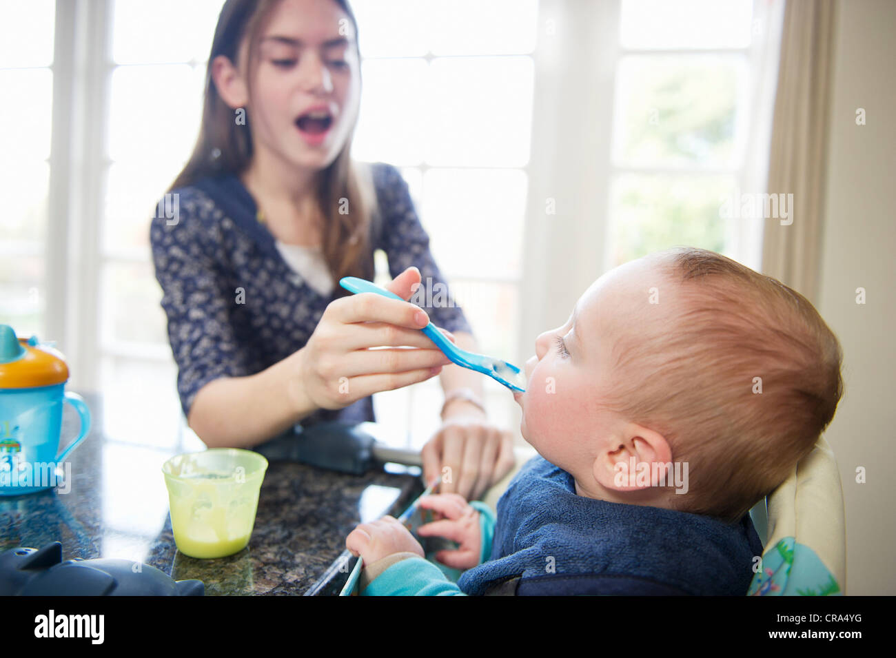 Girl feeding baby brother at table Stock Photo