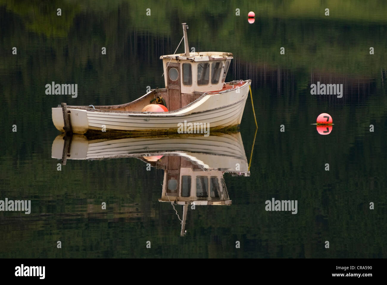 A fishing boat mirrored on Loch Leven on a still afternoon in Scotland. Stock Photo