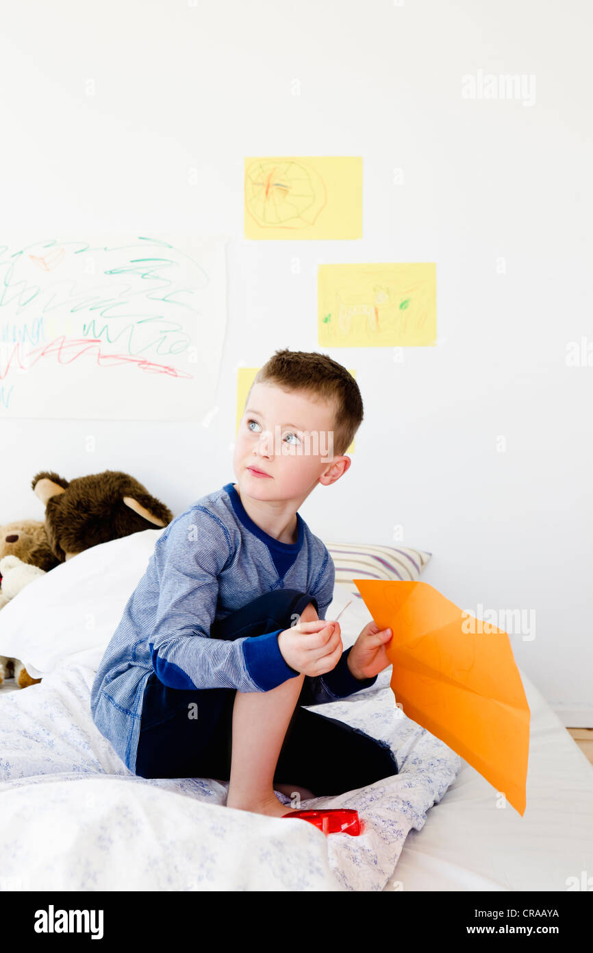 Boy holding drawing on bed Stock Photo
