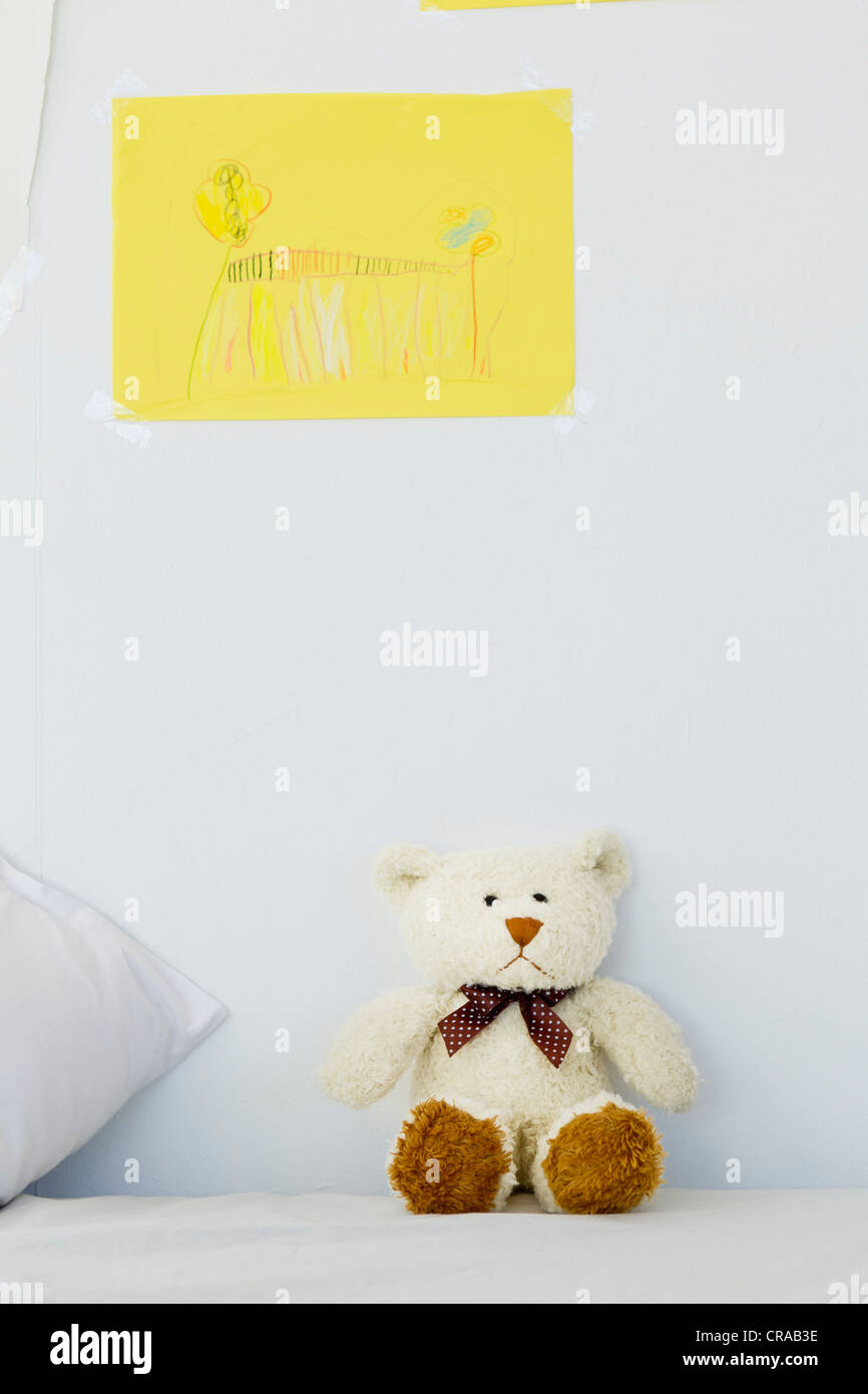 Teddy bear and childs drawing on bed Stock Photo