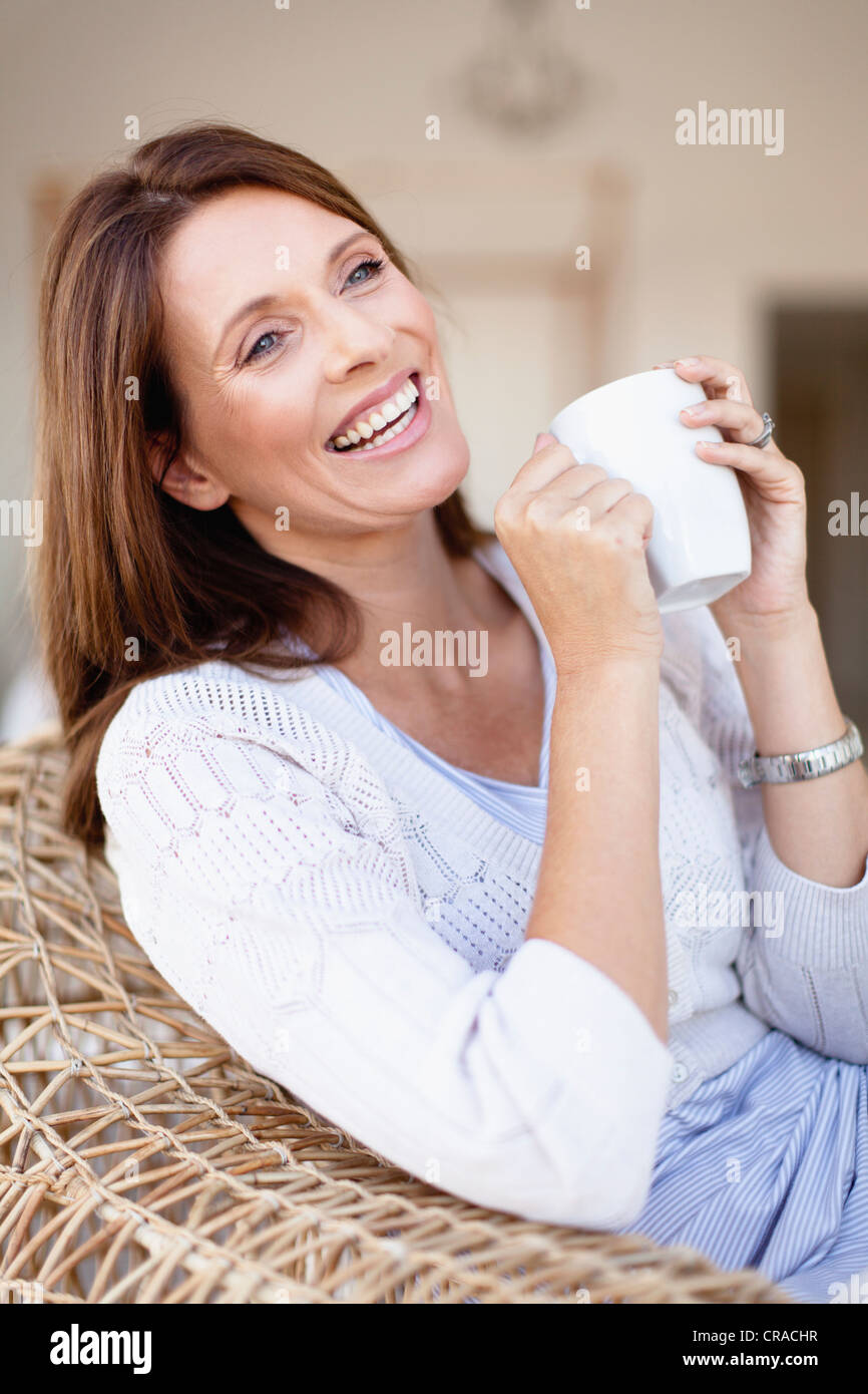 Older woman having coffee in armchair Stock Photo