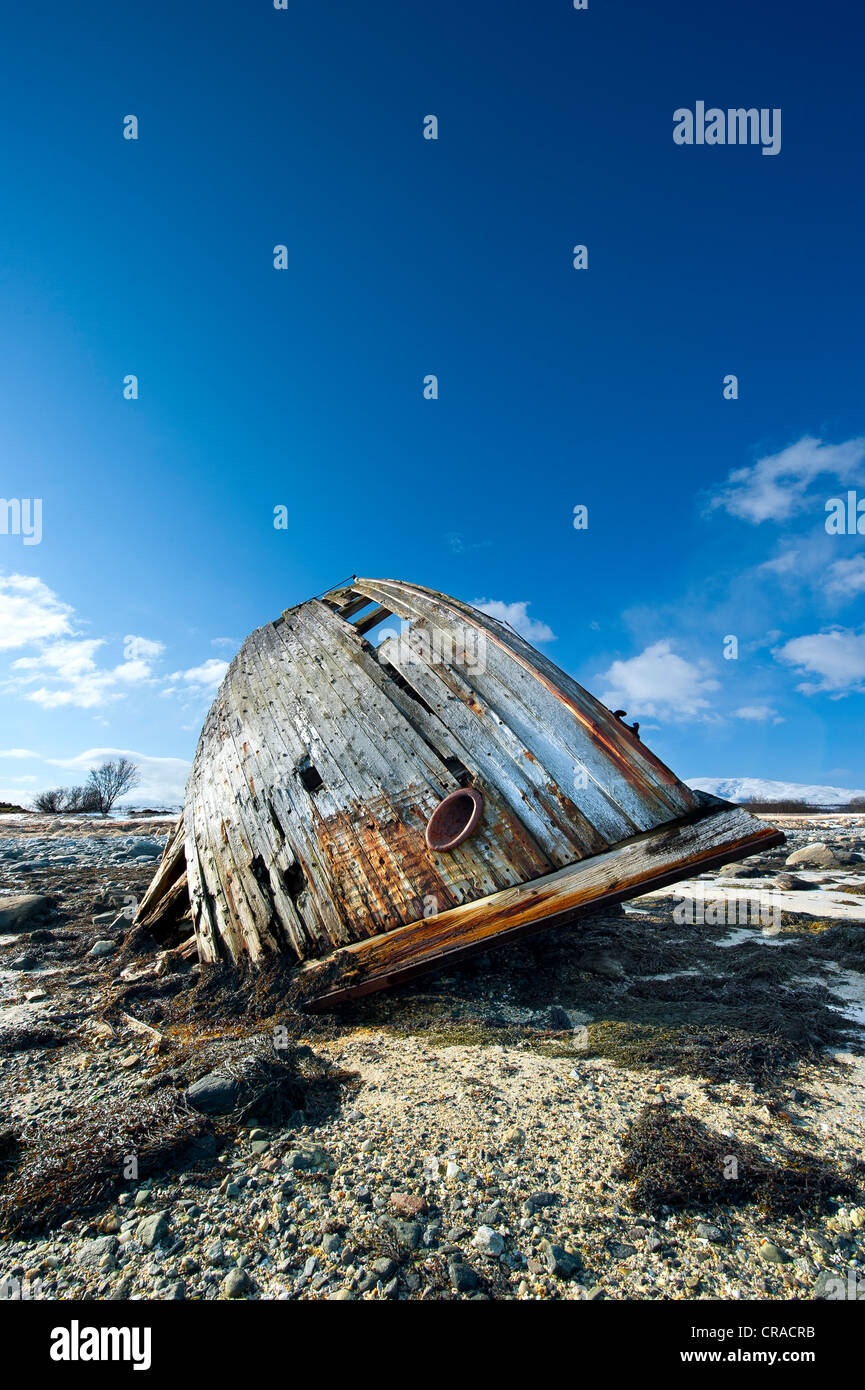Old ship wreck lying tilted on a shore at low tide Stock Photo