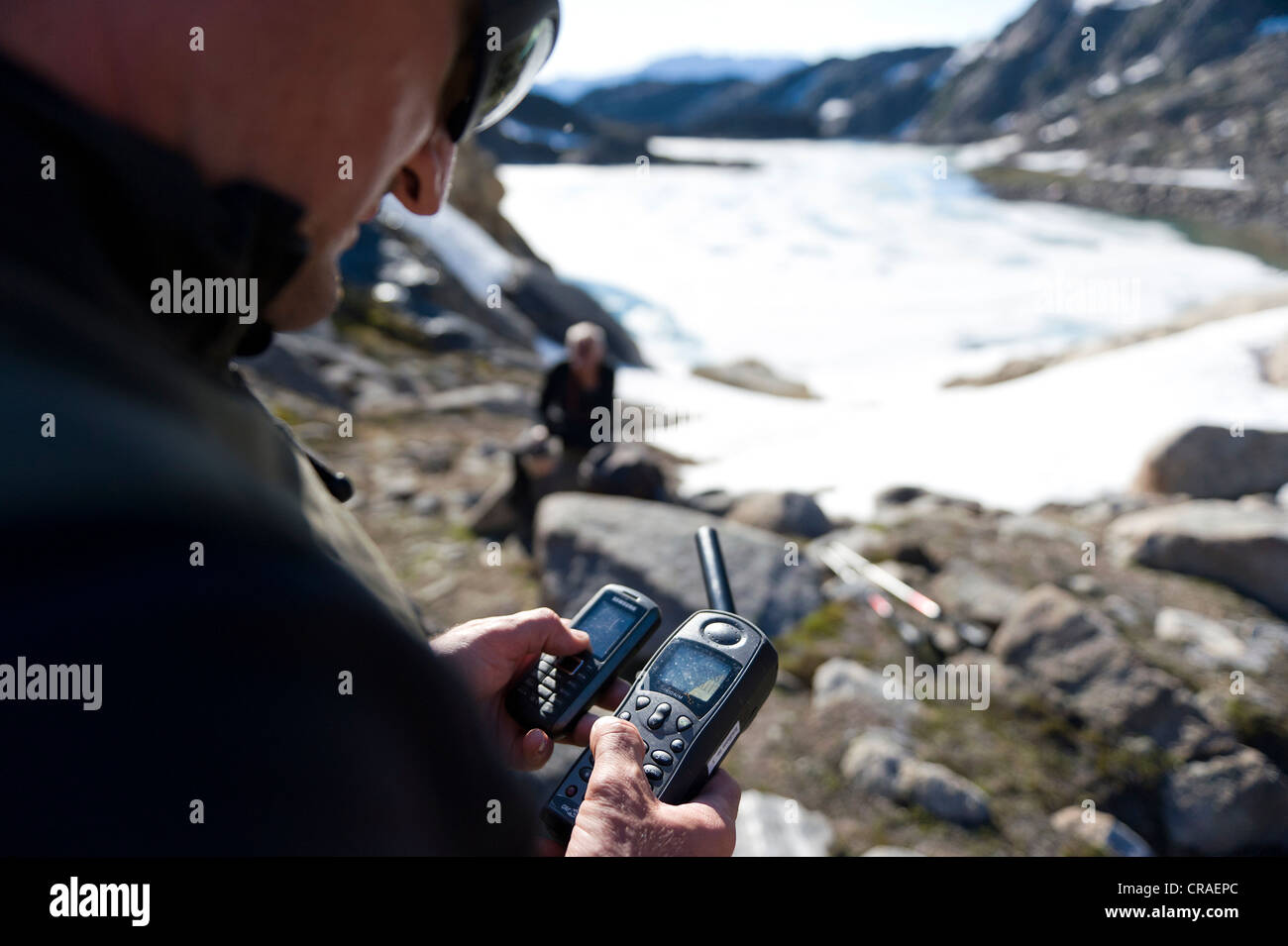 Hiking guide using a satellite phone, near Tasiilaq or Ammassalik, East