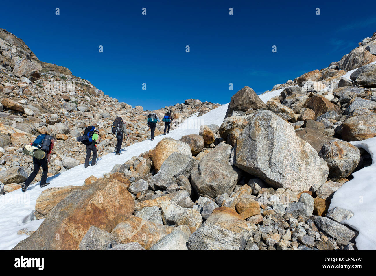 Field of snow and boulders, hikers at Mittivakkat Glacier, Ammassalik Peninsula, East Greenland, Greenland Stock Photo
