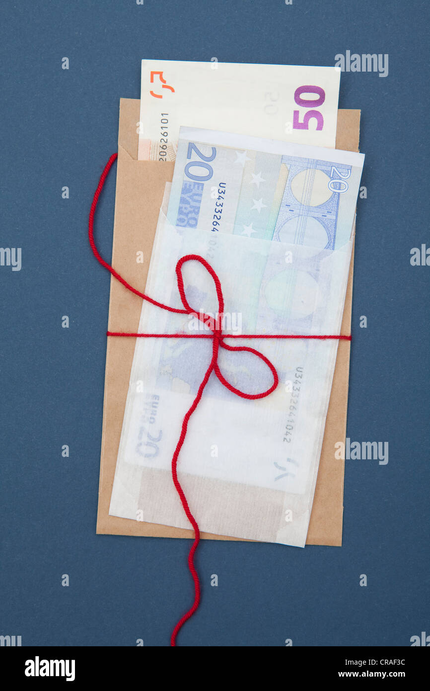 Envelope with banknotes and a ribbon, gift of money, bribery Stock Photo