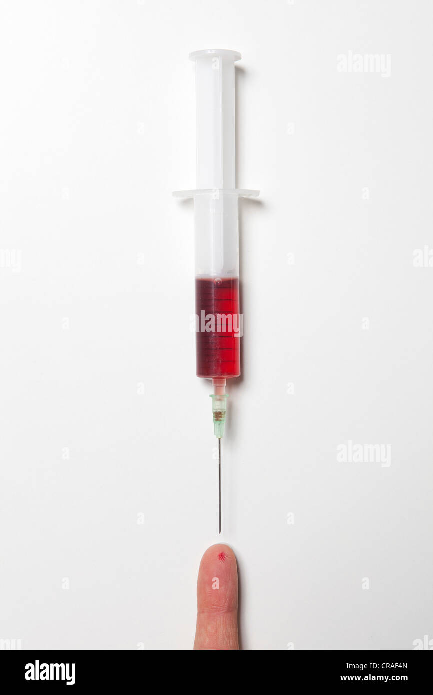 Syringe with blood, fingertip with trace of an injection, blood