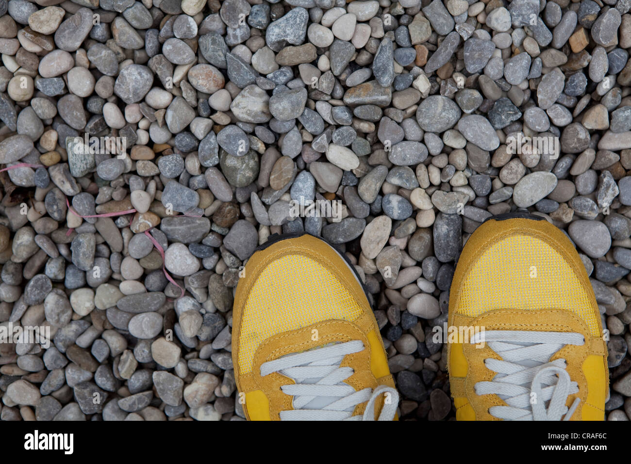 Yellow sneakers on gravel Stock Photo