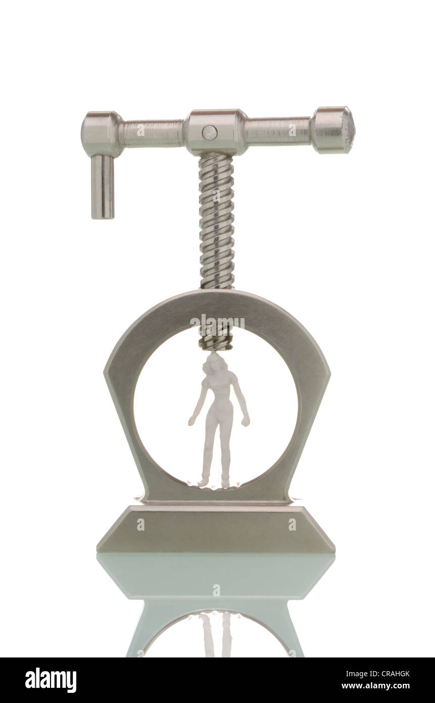 Miniature figure of a young woman clamped in a vice, symbolic image for young women under pressure Stock Photo