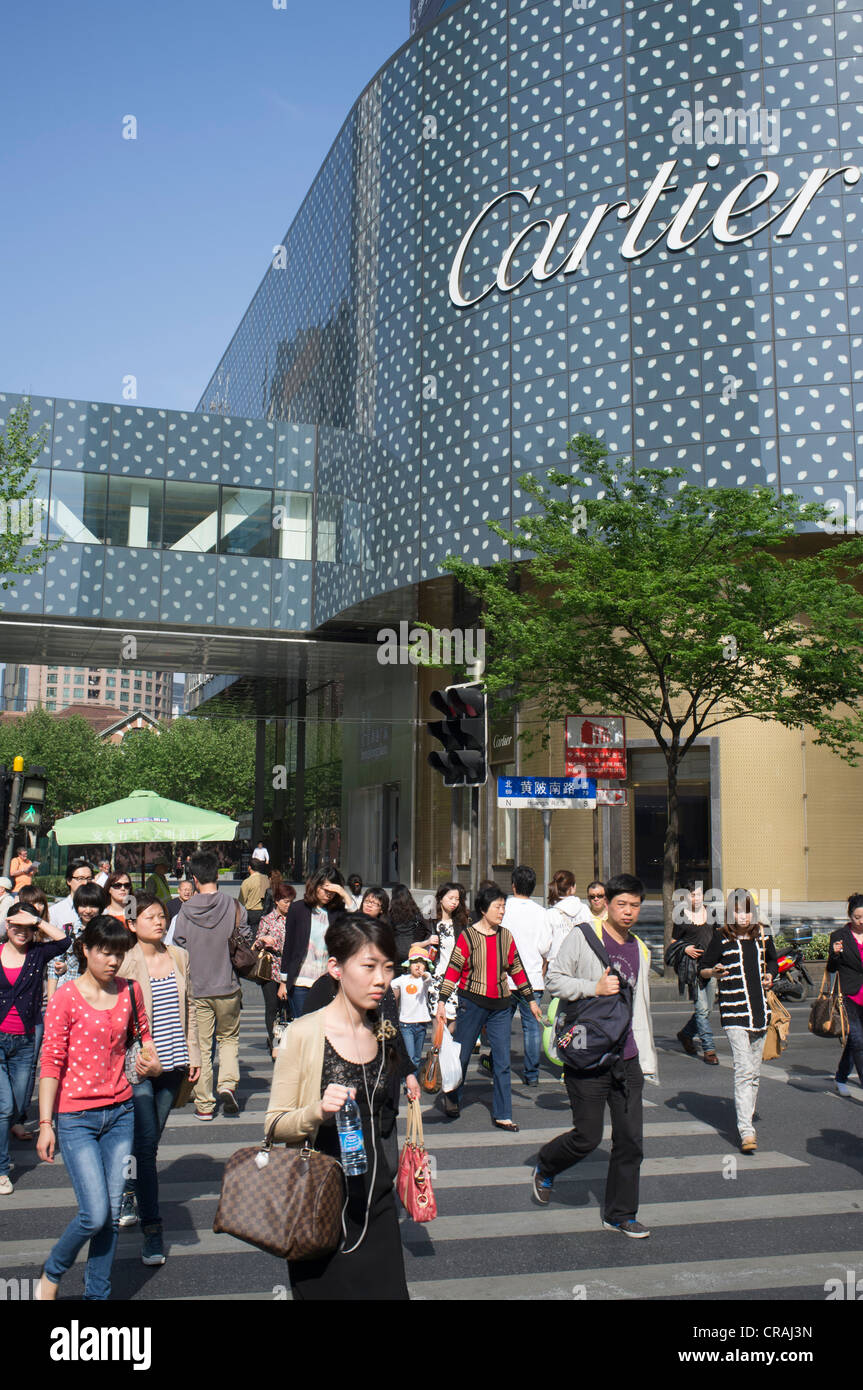 Pedestrians crossing Huaihua Street in central Shanghai beside upmarket Cartier shop in China Stock Photo