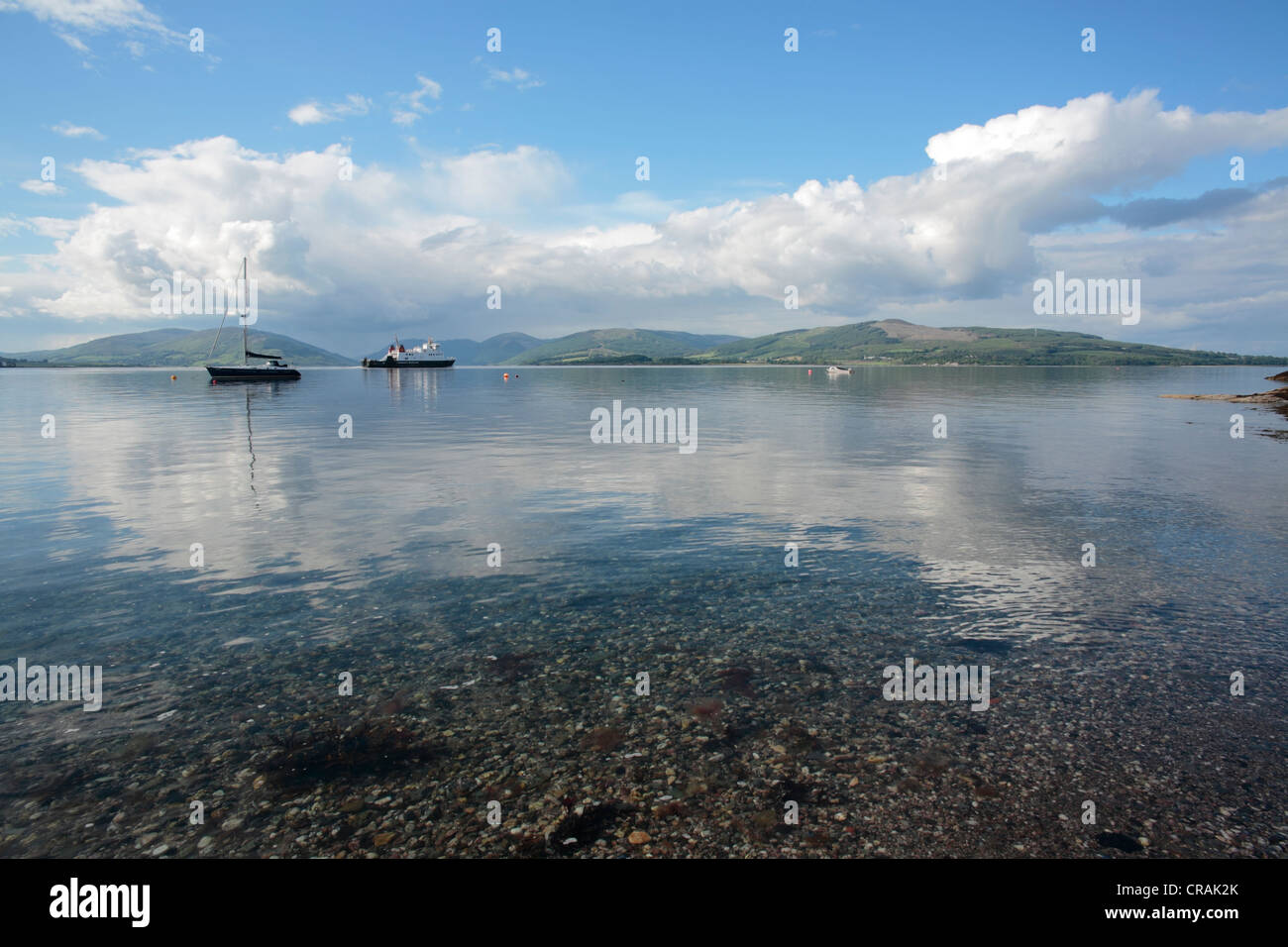 Rothesay bay and ferry leaving with a yacht moored up and Loch Striven in Cowal beyond Stock Photo
