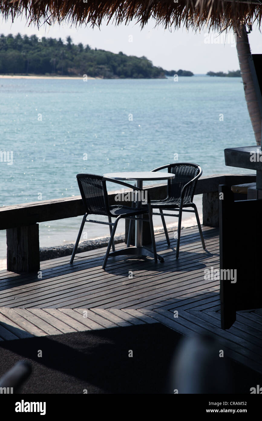 It's a photo of a bar table with 2 chair on a wood terrace near the sea. It's in a resort hotel in Koh Samui in Thailand Stock Photo