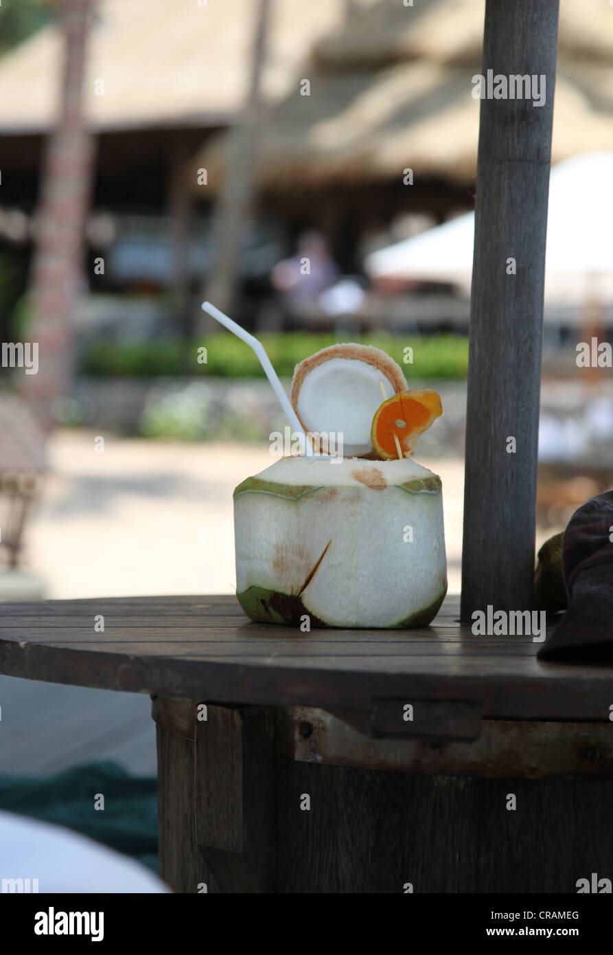 It's a photo of a refreshing milk coco in a coconut that is on a wood table in a resort hotel in Koh Samui in Thailand. Stock Photo