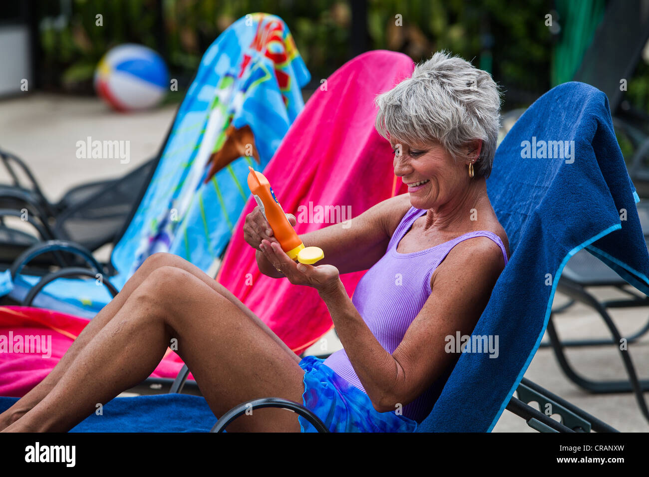 A sun bather prepares to apply suntan lotion. Stock Photo