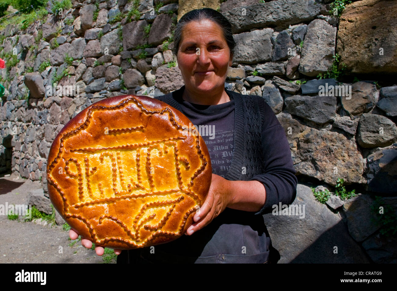 Smiling woman holding traditional bread, Geghard Monastery, Armenia, Middle East Stock Photo