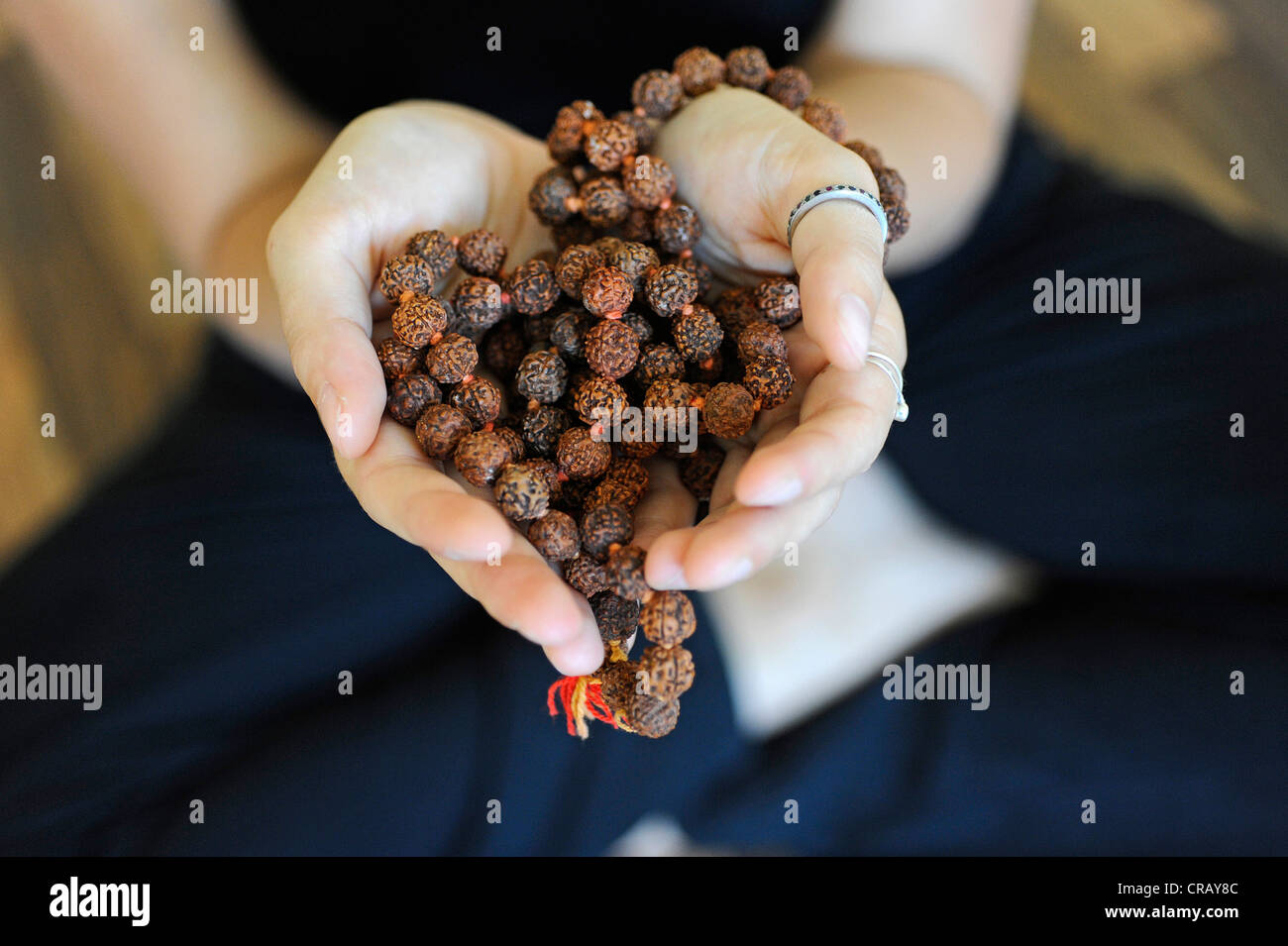 Yoga student holding chain of Rudraksha beads in cupped hands, yoga school Stock Photo